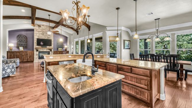 Kitchen featuring a large island with sink, a stone fireplace, a chandelier, open floor plan, and recessed lighting | Image 17