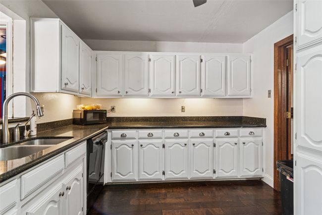 Kitchen with black appliances, dark stone counters, and white cabinets | Image 7