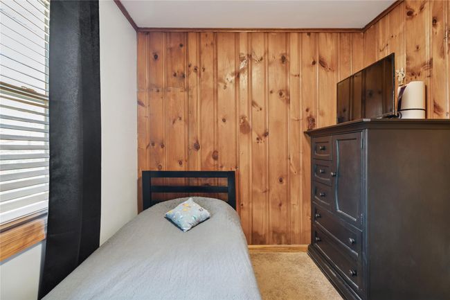 Bedroom with wooden walls and light colored carpet | Image 27