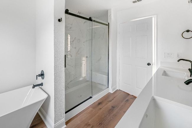 Full bathroom with dual sinks, a freestanding bath, a marble finish shower, and wood finished floors | Image 18