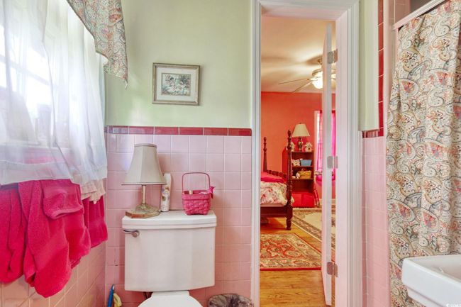 Full bathroom with tile walls, toilet, a ceiling fan, wainscoting, and wood finished floors | Image 25