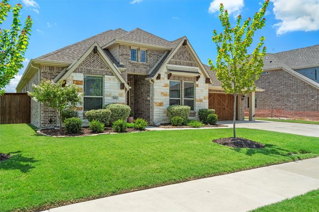 View of front of property with driveway, stone siding, a shingled roof, and a garage | Image 4