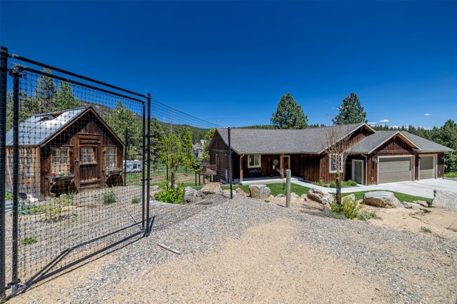 Ranch-style house with driveway, an attached garage, board and batten siding, covered porch, and a gate | Image 55