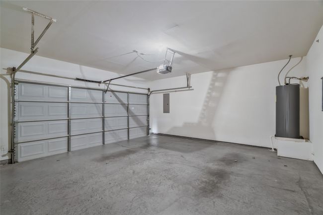 Garage featuring water heater, electric panel, and a garage door opener | Image 26