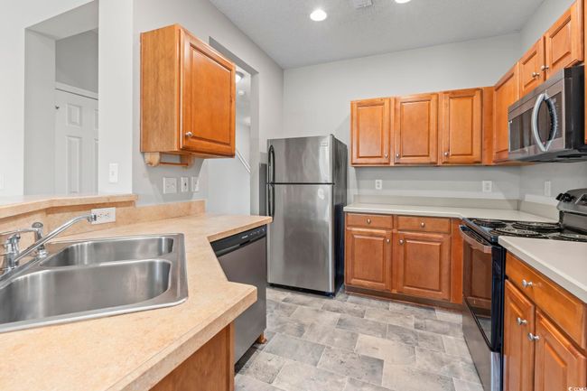 Kitchen with appliances with stainless steel finishes, a sink, light countertops, brown cabinetry, and recessed lighting | Image 9
