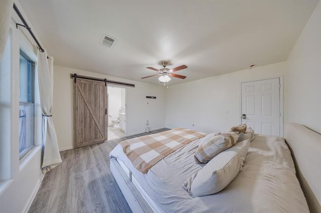 Primary bedroom with wood-like flooring, combining warmth and durability for a cozy atmosphere. | Image 21