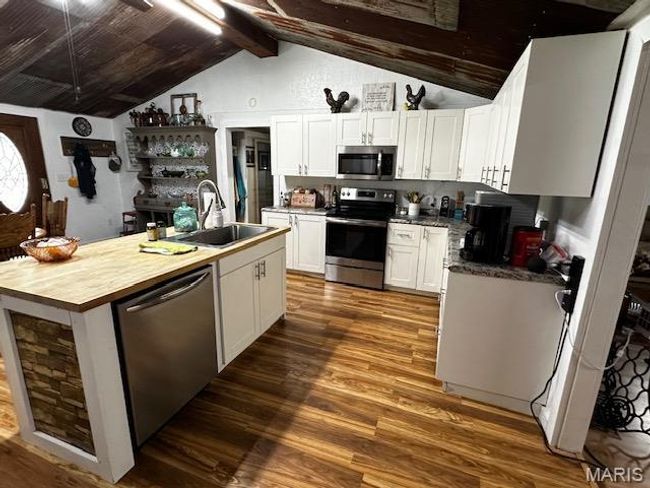 Kitchen with vaulted ceiling with beams, white cabinets, sink, stainless steel appliances, and dark hardwood / wood-style floors | Image 12