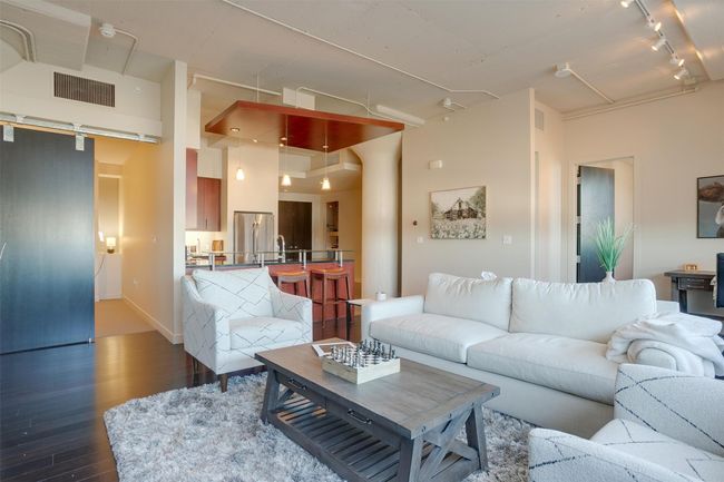 Living room featuring dark wood-style flooring, track lighting, and a high ceiling | Image 20