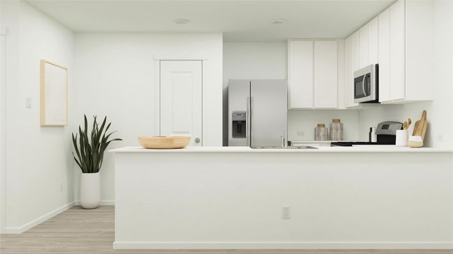 Kitchen with refrigerator with ice dispenser, stainless steel microwave, a peninsula, light wood-type flooring, and stove | Image 15