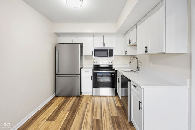 kitchen with white cabinets, a sink, appliances with stainless steel finishes, light wood-style floors, and light countertops | Image 7