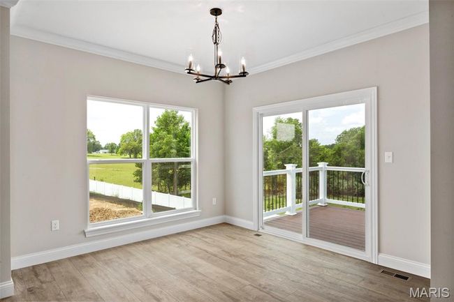 Spare room featuring a chandelier, healthy amount of natural light, wood finished floors, and ornamental molding | Image 16