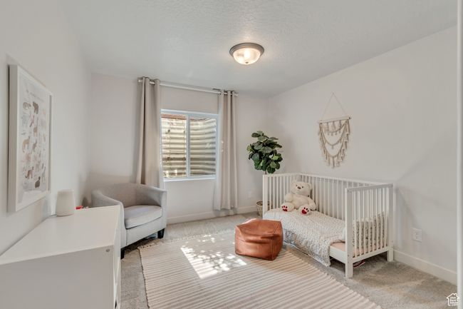 Bedroom with carpet flooring, a textured ceiling, and a nursery area | Image 22