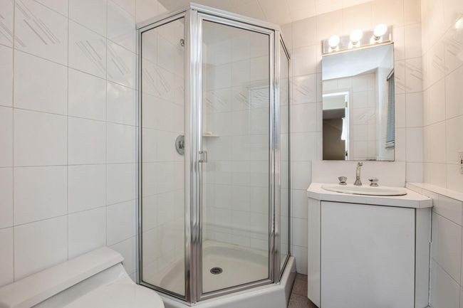 Full bathroom with a shower stall, toilet, vanity, and tile walls | Image 17