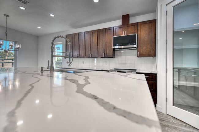 Kitchen featuring appliances with stainless steel finishes, decorative backsplash, light stone counters, and pendant lighting | Image 20