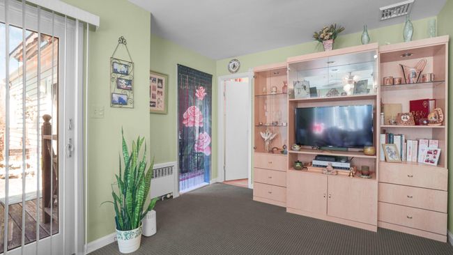 Living room featuring carpet flooring, visible vents, and radiator heating unit | Image 13