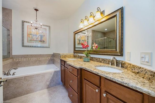 Bathroom with vanity, an inviting chandelier, tile patterned floors, and shower with separate bathtub | Image 14