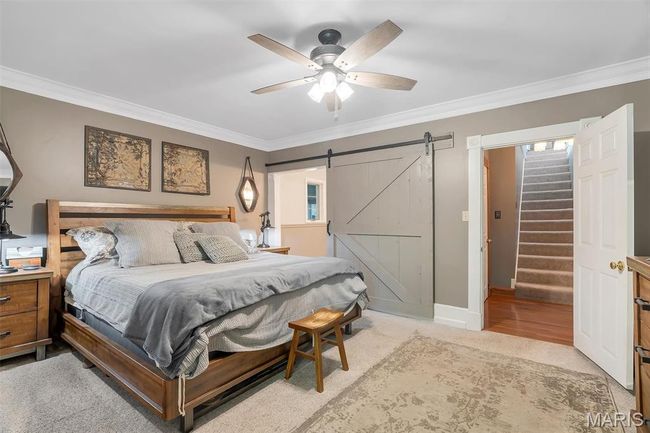 Bedroom with ornamental molding, a barn door, light colored carpet, and a ceiling fan | Image 58