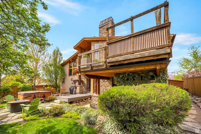 Rear view of house with fence, a wooden deck, a hot tub, and stone siding | Image 38