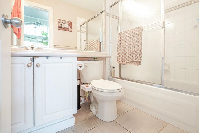 Bathroom featuring shower / bath combination with glass door, vanity, toilet, and tile patterned flooring | Image 4
