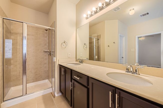 Bathroom featuring tile patterned flooring, double vanity, and a shower stall | Image 16