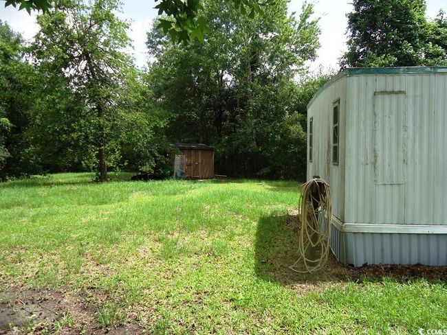 View of green lawn with a storage unit | Image 6