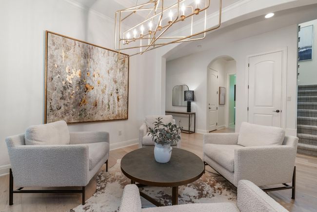 Living or dining area with arched walkways, wood finished floors, baseboards, ornamental molding, and stairway | Image 5