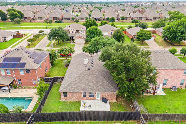 Aerial view showcasing the spacious fenced backyard, concrete patio, and surrounding mature trees for added privacy. | Image 36