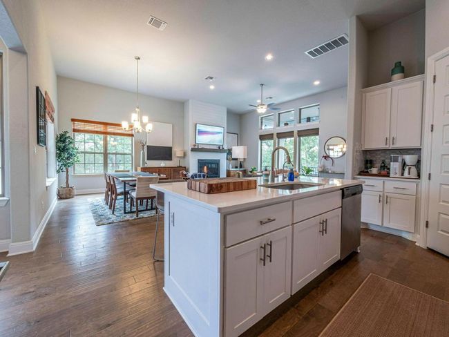 Kitchen with dishwasher, a ceiling fan, a glass covered fireplace, white cabinets, and plenty of natural light | Image 7