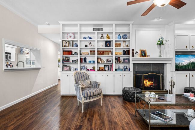 Living area with ornamental molding, dark wood finished floors, ceiling fan, and a tile fireplace | Image 9