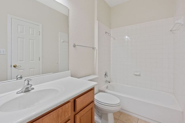 Bathroom featuring toilet, tile patterned flooring, vanity, and shower / washtub combination | Image 31