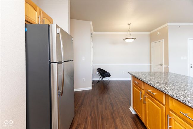 kitchen with dark stone counters, freestanding refrigerator, dark wood-type flooring, ornamental molding, and baseboards | Image 11