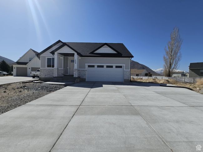 Single story home featuring concrete driveway, stone siding, and a garage | Image 25