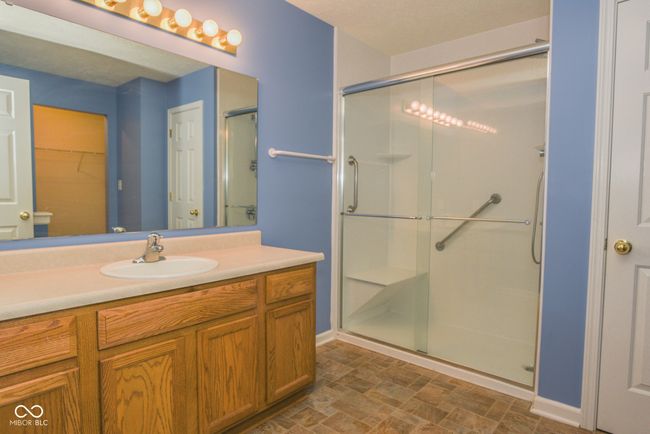 bathroom with a stall shower, stone finish floors, vanity, and baseboards | Image 8