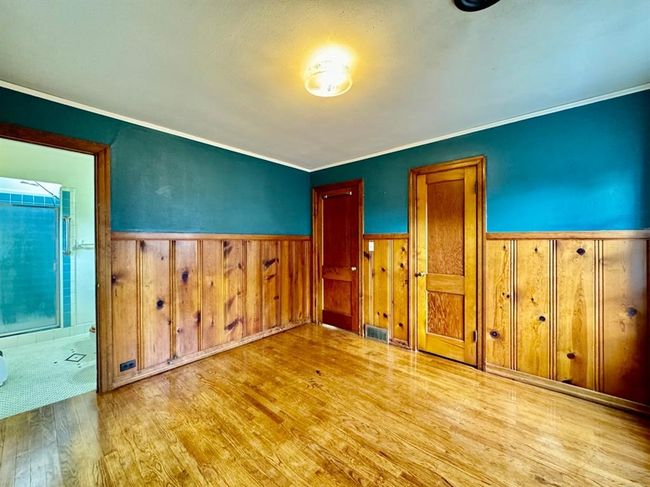 Unfurnished bedroom with wood finished floors, wainscoting, ornamental molding, and wood walls | Image 15