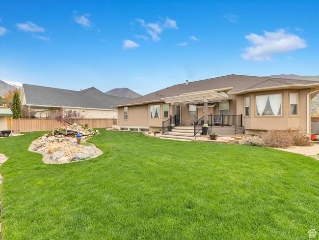 Back of house with a pergola, fence, a wooden deck, a yard, and stucco siding | Image 43