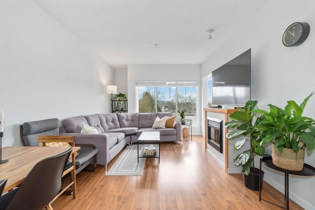 Living area with light wood-style flooring, baseboards, and a glass covered fireplace | Image 4