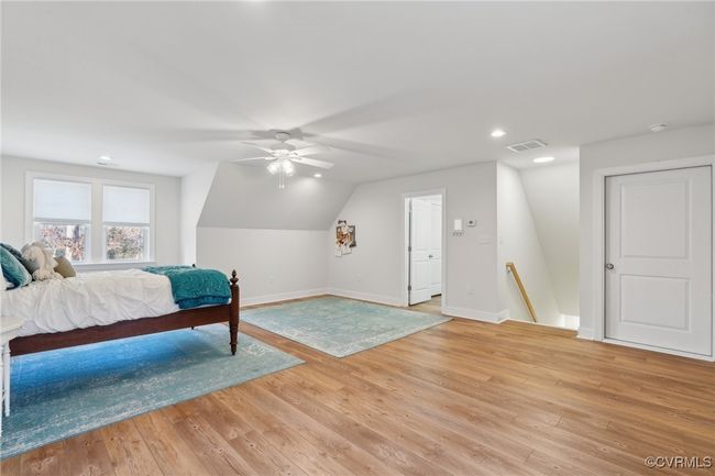 Bedroom with visible vents, baseboards, vaulted ceiling, and light wood finished floors | Image 38