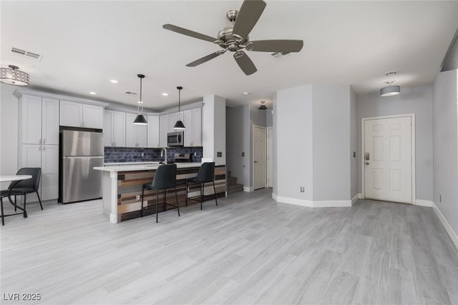 Kitchen with backsplash, light countertops, a breakfast bar, visible vents, and appliances with stainless steel finishes | Image 6