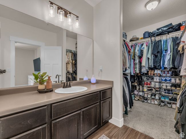 Bathroom featuring a walk in closet, vanity, and wood finished floors | Image 10