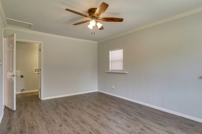 Unfurnished room with dark wood-style floors, a ceiling fan, ornamental molding, and attic access | Image 18