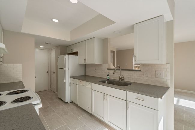 Enjoy a seamless cooking experience in this light-filled kitchen with ample storage, modern fixtures, and open sight lines to the living space. | Image 6