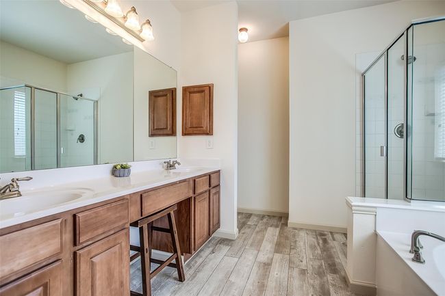 Primary en-suite bathroom featuring double sinks, long vanity & LV flooring. | Image 22