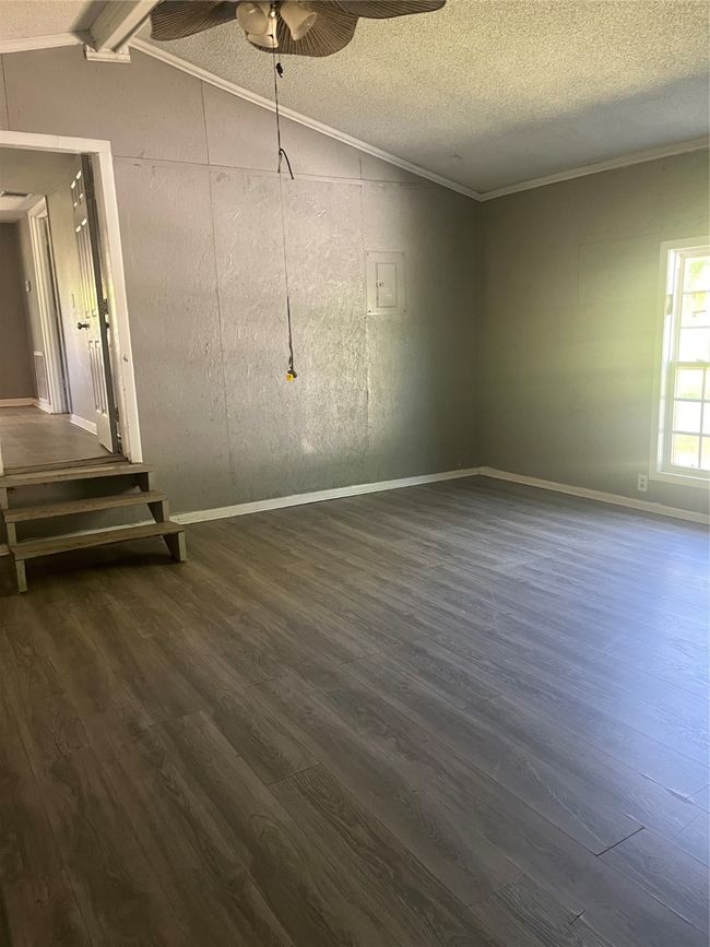 Spare room with vaulted ceiling, crown molding, a ceiling fan, and dark wood-type flooring | Image 10