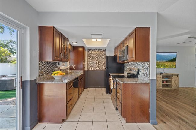 The kitchen has granite countertops with a stone & glass backsplash. | Image 11