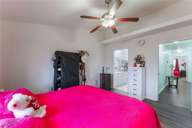 Bedroom with connected bathroom, ceiling fan, wood finished floors, and baseboards | Image 20