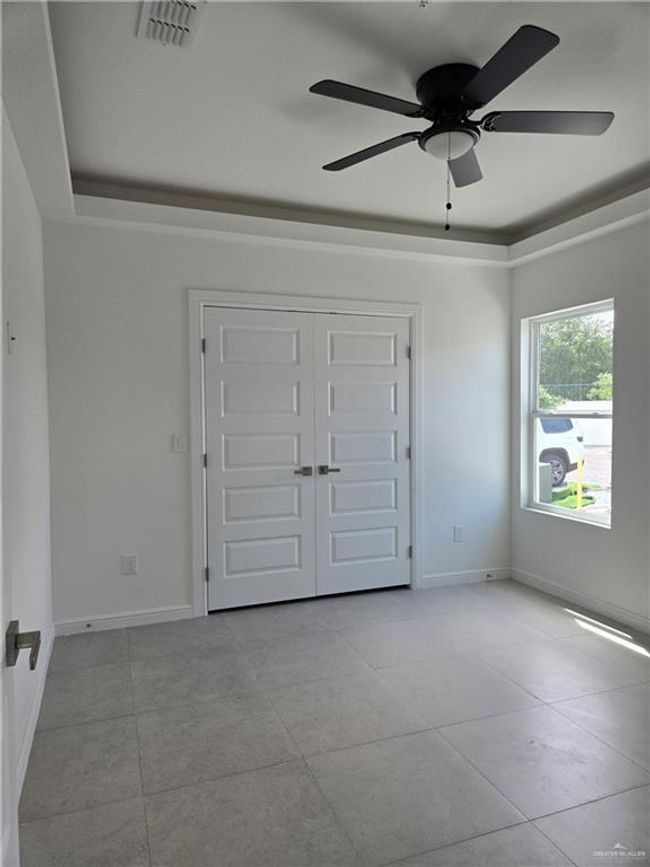 Unfurnished bedroom with tile patterned flooring, ceiling fan, and a closet | Image 9