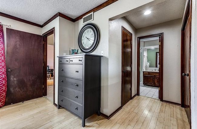 Corridor with light wood-style floors, a textured ceiling, ornamental molding, and baseboards | Image 8
