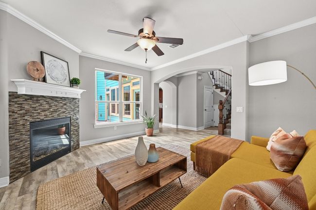 Living room featuring arched walkways, crown molding, ceiling fan, gas log fireplace | Image 8