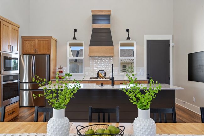Kitchen featuring stainless steel appliances, a high ceiling, dark wood finished floors, a sink, and backsplash | Image 9