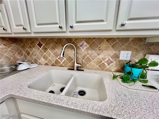 Kitchen with solid surface countertops and stone tile backsplash. | Image 6
